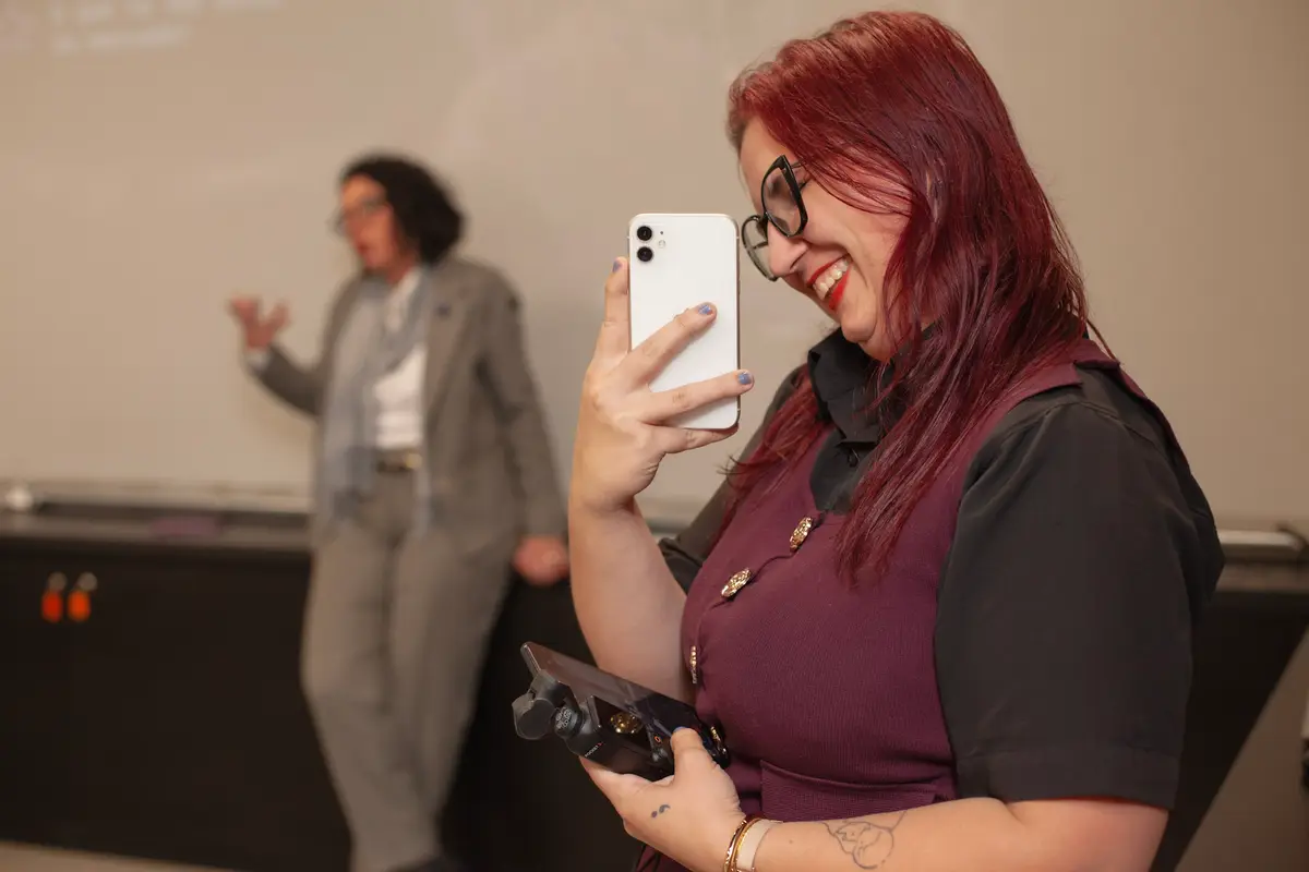 Maia filmando com o celular uma palestra