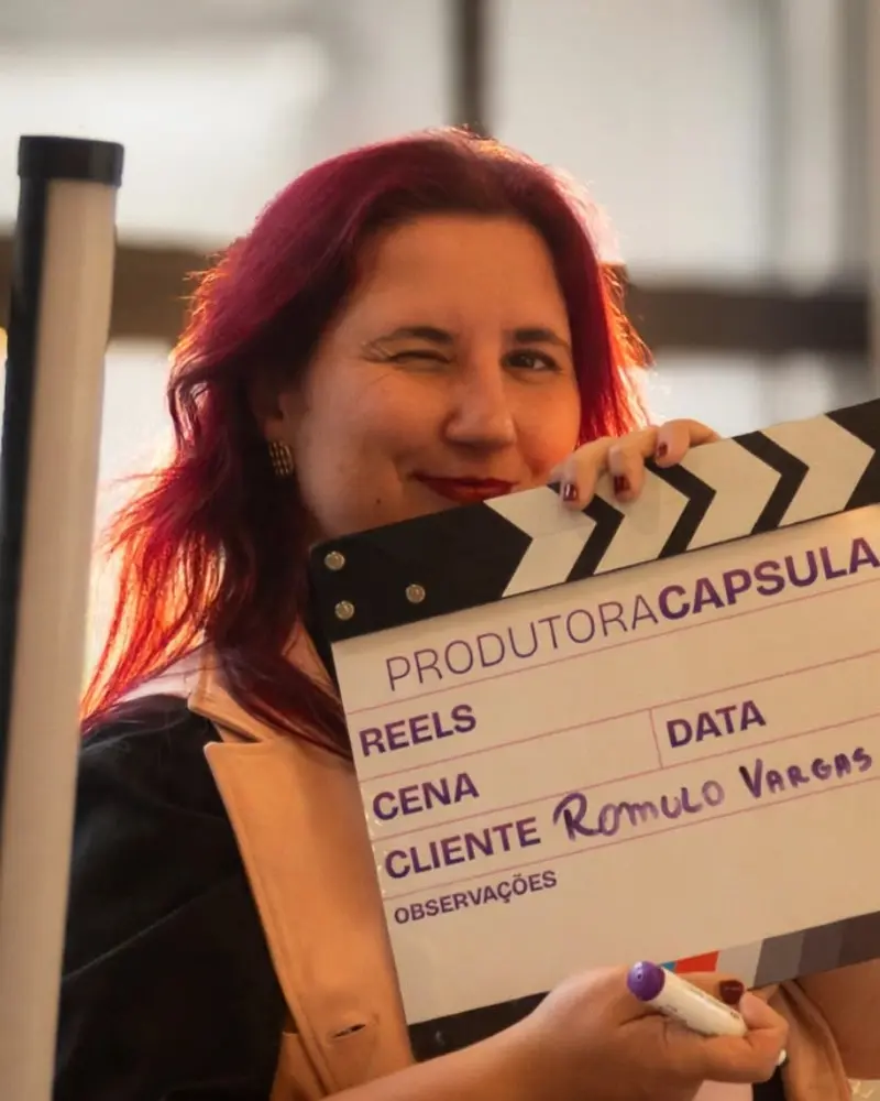 Maia segurando a claquete da Produtora Capsula