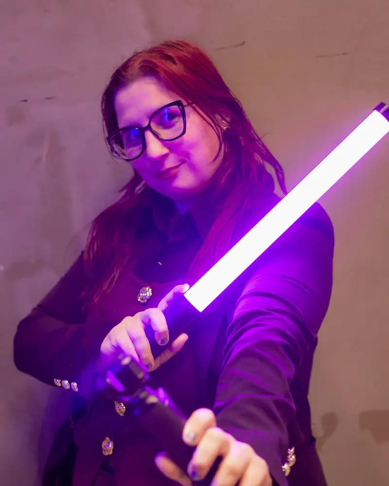 Maia segurando um sabre de luz roxo, em ensaio da Produtora Capsula